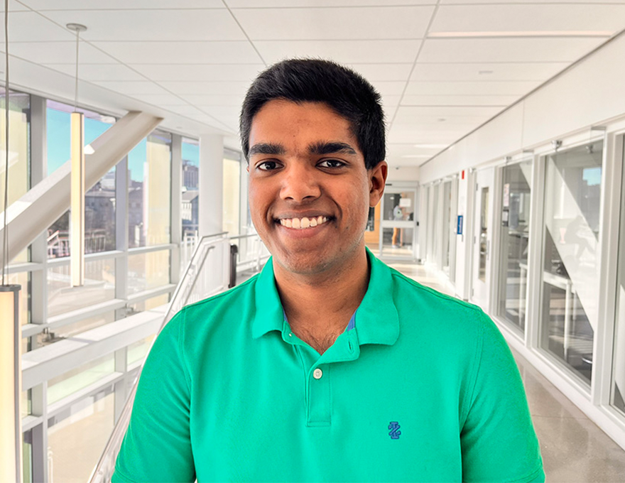 A young man smiles in a bright hallway.