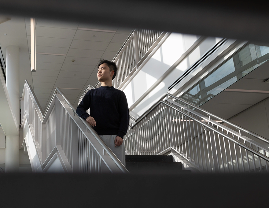 A man in a black sweater looks to the left from a flight of stairs.